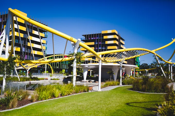 Yellow canopy structures over the Village Heart lawn with precinct buildings behind